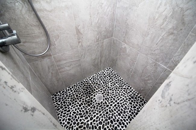 Main-Image-for-Black-River-Rock-Shower-Floor-Against-Gray-Tiles
